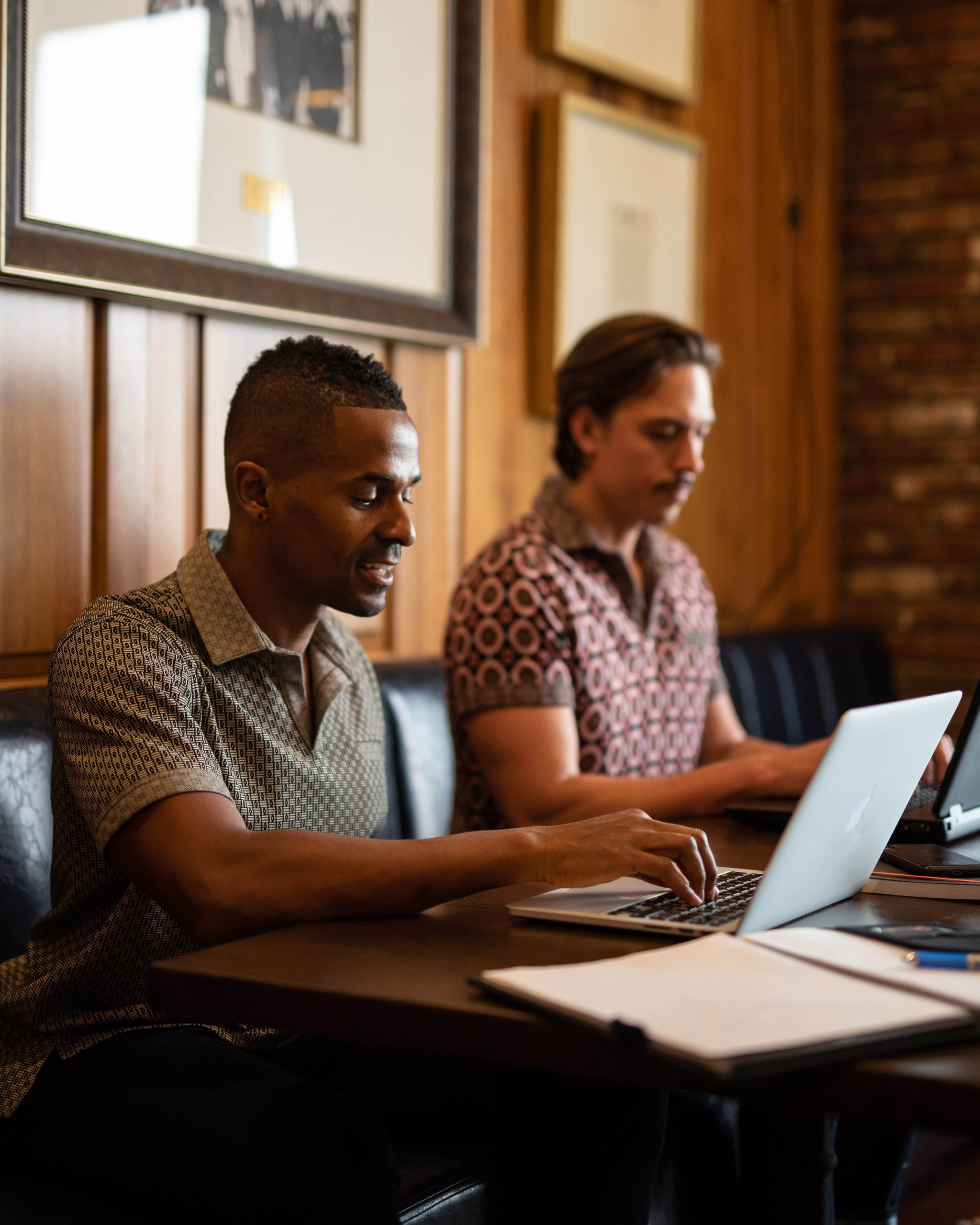 Two men working on laptops at a table AT LA co-worker space.